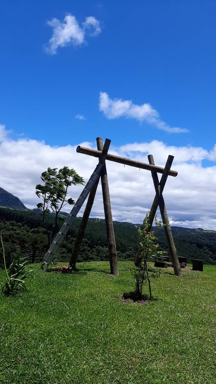 O balanço em madeira no gramado, de frente pra serra
