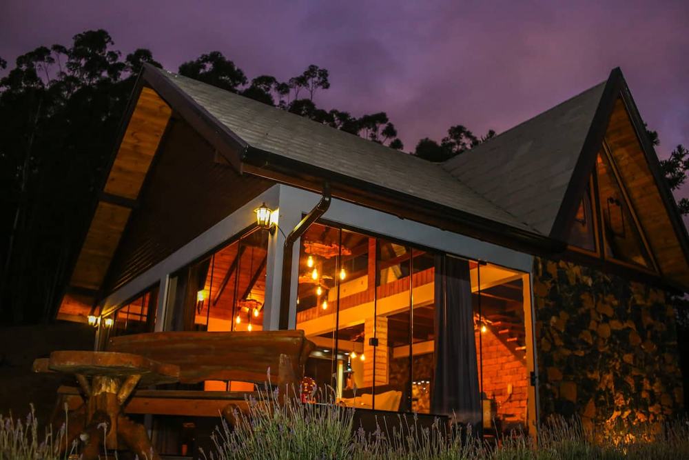 Cabana Horizonte, telhado em A, acesa ao anoitecer