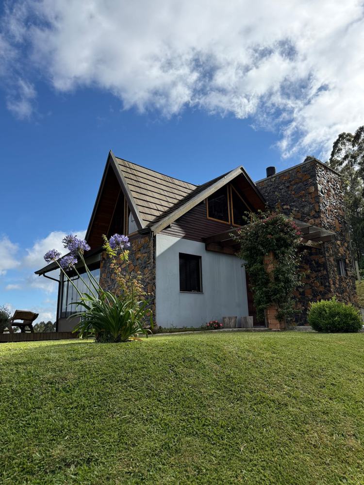 A fachada de dia, entre pedra, vidro e madeira